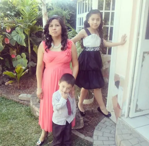Adriel as a toddler in a shirt and tie with his mother and sister