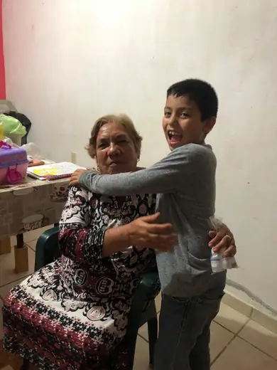 Adriel laughing while hugging his grandmother