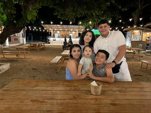 Family at an outdoor table under string lights