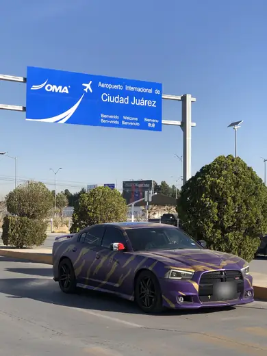Airport welcome sign in Ciudad Juárez above a purple car