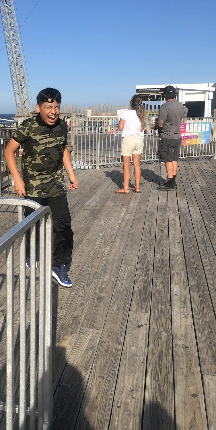 Adriel laughing as he walks off a boardwalk ride