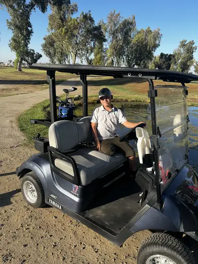 Adriel at the wheel of a golf cart