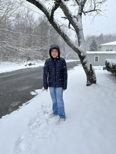 Adriel standing in the snow with his hood up