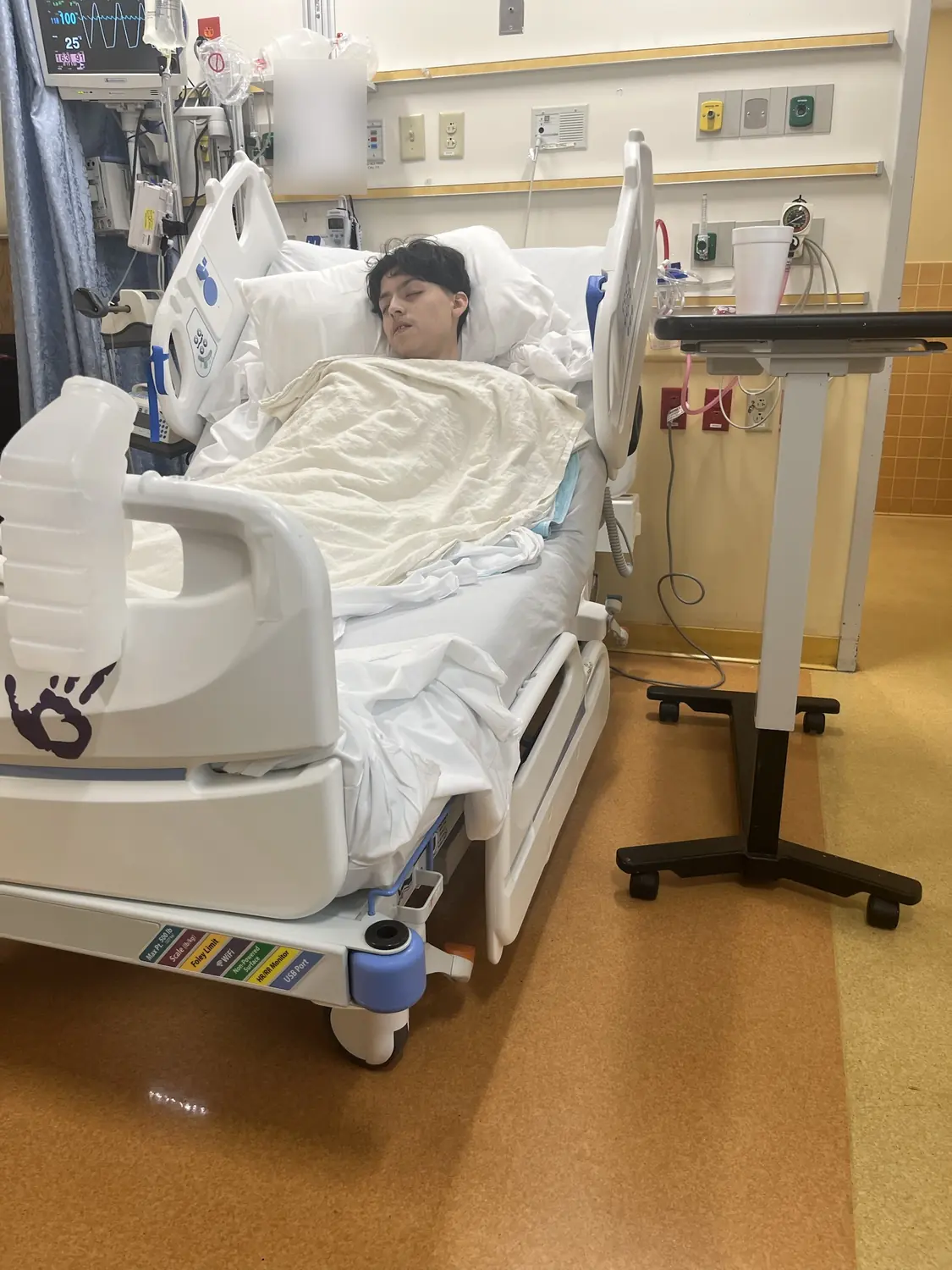 Adriel asleep in an intensive care bed, connected to a monitor