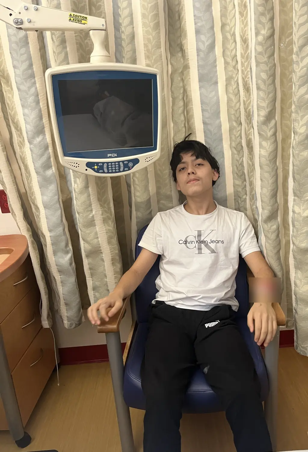 Adriel leaning back in a hospital chair, January 2025