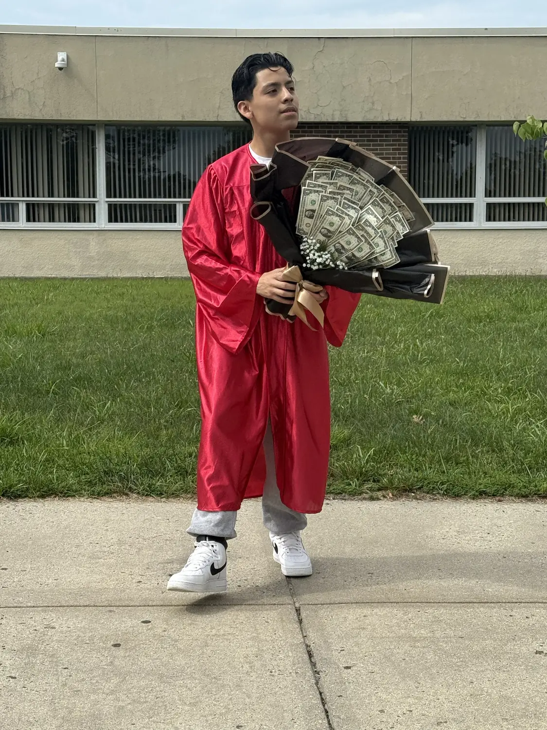 Adriel in a red graduation gown, mid-step, looking to the side