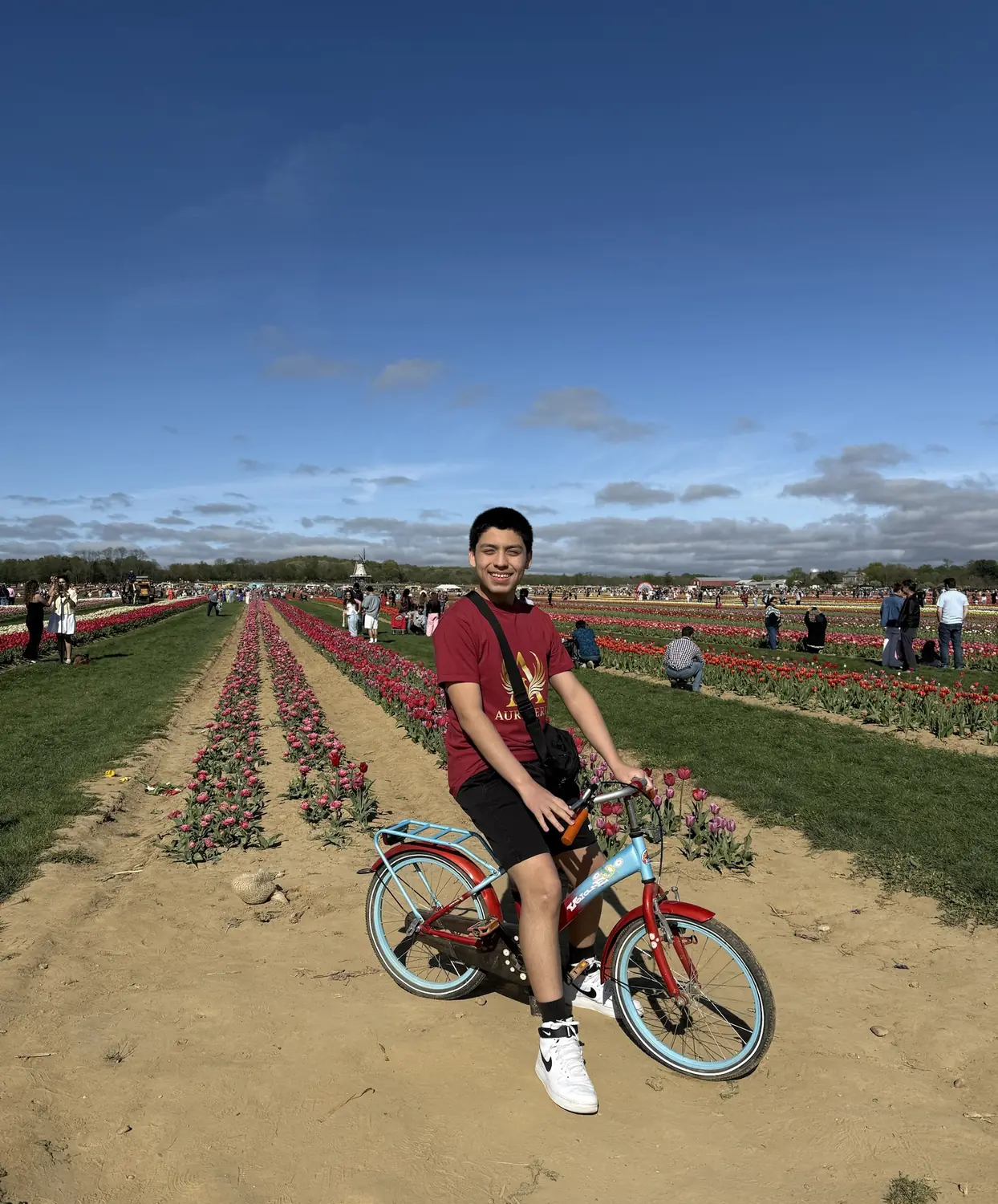 Adriel on a bicycle in a tulip field wearing an Aureveris T-shirt