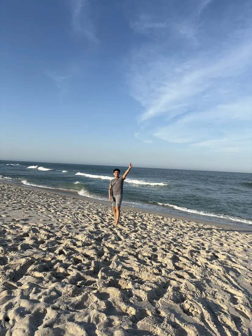 Adriel on the beach with his arm raised